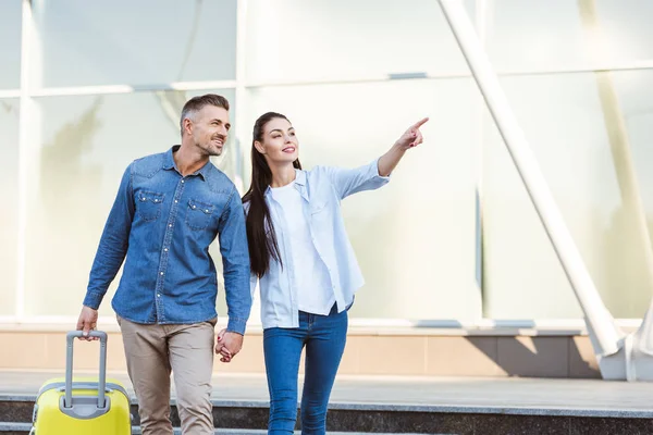 A couple of tourists looking away, smiling and pointing at something — Stock Photo