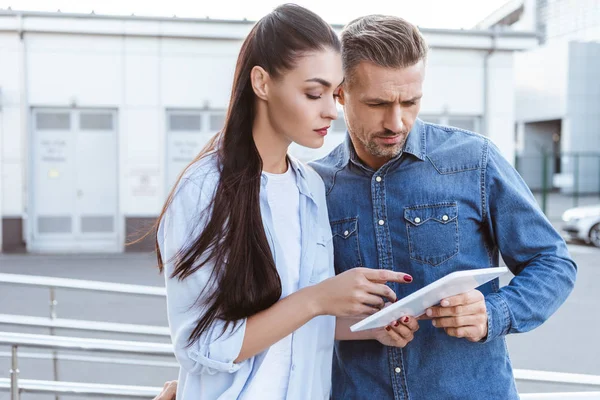 Couple regardant attentivement dans tablette numérique, femme pointant vers l'écran — Photo de stock