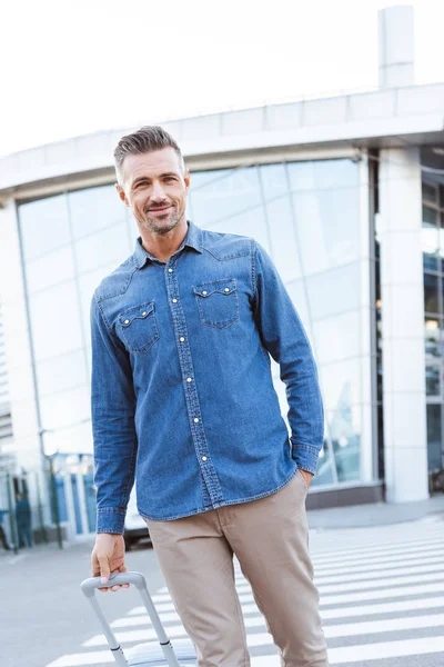 Bel homme adulte avec des bagages souriant à la caméra — Photo de stock