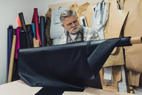 Focused mature craftsman working with leather at workshop — Stock Photo