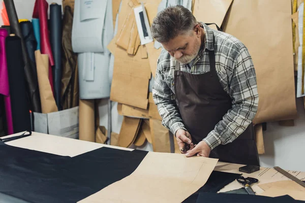 Homem handbag artesão em avental trabalhando com papelão no estúdio — Fotografia de Stock