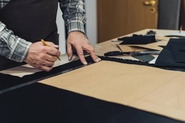 Partial view of handbag craftsman making measurements by pencil and ruler in studio — Stock Photo