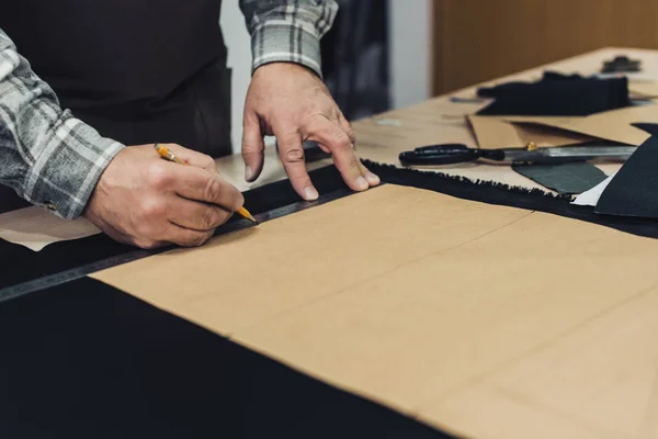 Zugeschnittenes Bild eines Handtaschenhandwerkers, der im Atelier mit Bleistift und Lineal Maß nimmt — Stockfoto