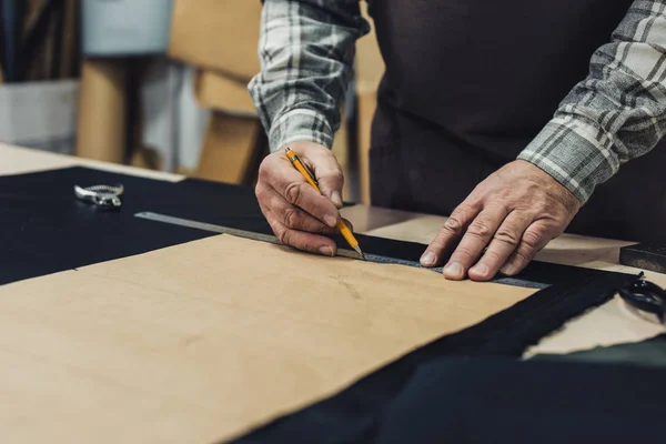 Teilansicht des Handtaschenhandwerkers, der im Atelier mit Bleistift und Lineal Maß nimmt — Stockfoto