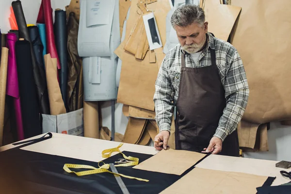 Зрелая кожаная сумочка ремесленник в фартуке работает в студии — стоковое фото