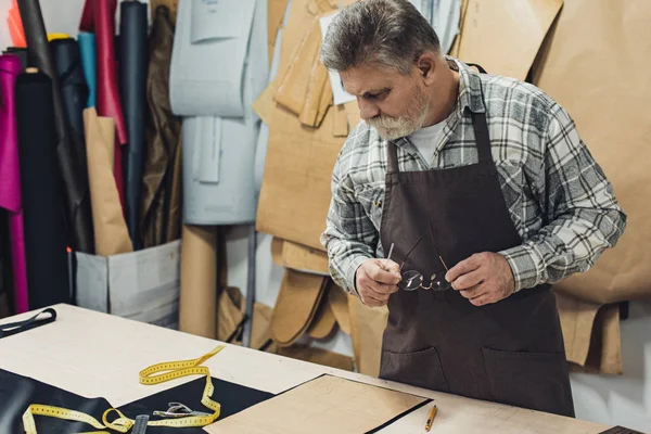 Borsa uomo in pelle artigiano in grembiule che lavora in studio — Foto stock