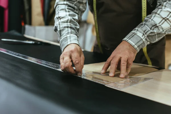 Cropped image of handbag craftsman making measurements on leather at workshop — Stock Photo