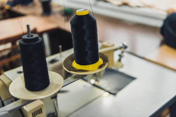 Messa a fuoco selettiva delle corde da cucito nere presso il laboratorio sartoriale — Foto stock