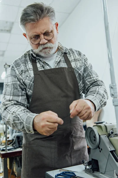 Low angle view of middle aged male tailor working near sewing machine at studio — Stock Photo