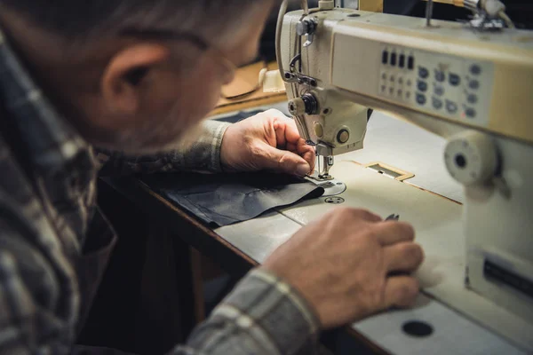 Partial view off male handbag craftsman working on sewing machine at studio — Stock Photo