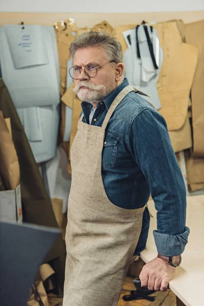 Confident middle aged male craftsman in apron posing at workshop — Stock Photo