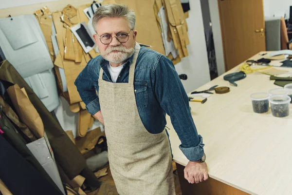 Vista de ángulo alto de artesano masculino de mediana edad feliz en delantal posando en el taller - foto de stock