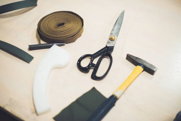 Close up view of working table with fabric, hammer and scissors at workshop — Stock Photo