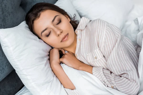 Schöne junge Frau im Schlafanzug schlafend auf dem Bett — Stockfoto