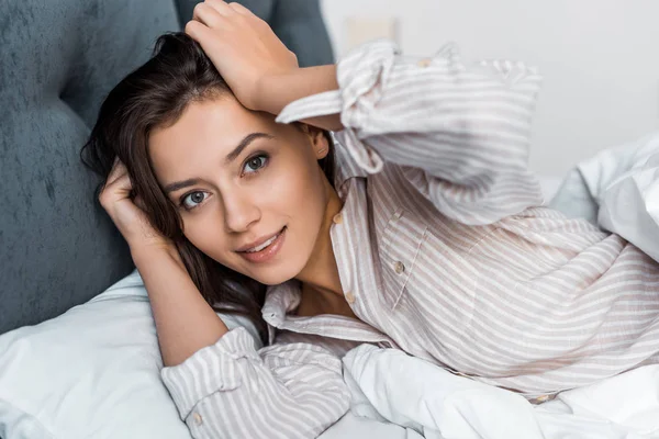 Belle fille brune en pyjama se détendre au lit — Photo de stock