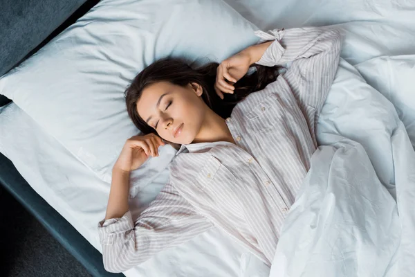 Вид зверху красива брюнетка в піжамі спить на ліжку вранці — стокове фото