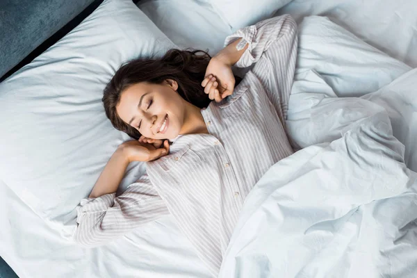 Jolie jeune femme en pyjama se réveillant au lit le matin — Photo de stock