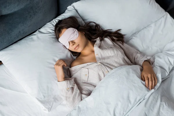 Belle jeune femme dormant dans un masque pour les yeux au lit — Photo de stock