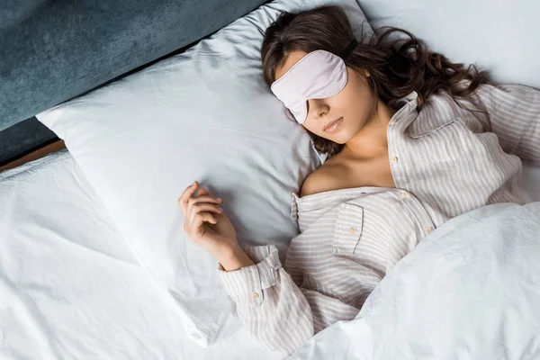 Молодая брюнетка женщина спит в маске глаза в постели — стоковое фото