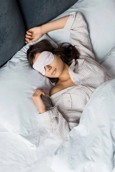 Attraktive junge Frau schläft in Augenmaske im Bett — Stockfoto