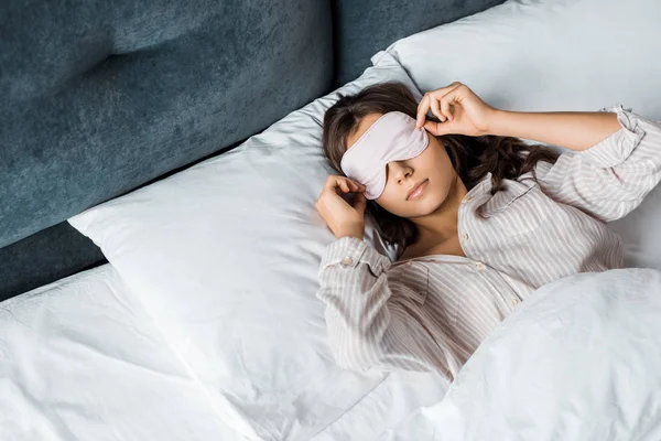 Young woman in sleeping eye mask waking up in bed in the morning — Stock Photo