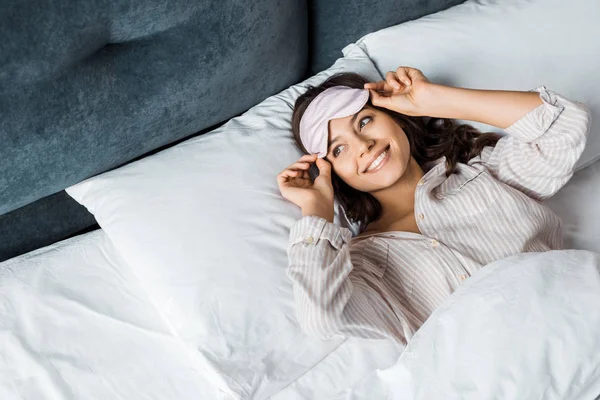 Smiling girl in sleeping mask waking up in bed in the morning — Stock Photo