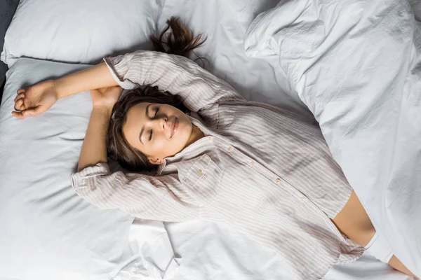 Вид зверху на молоду привабливу жінку в піжамі, що спить на ліжку вранці — стокове фото