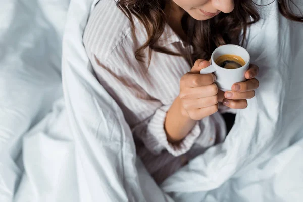 Vista ritagliata della ragazza che tiene in mano una tazza di caffè espresso al mattino — Foto stock