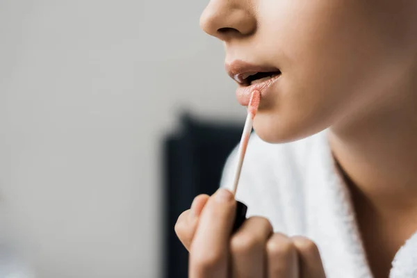 Cropped view of girl applying lip gloss — Stock Photo