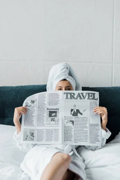 Jeune femme se cachant derrière le journal de voyage le matin — Photo de stock