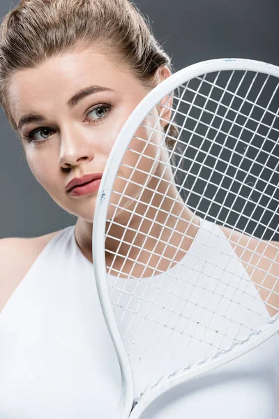 Bela jovem mulher oversize segurando raquete de tênis isolado em cinza — Fotografia de Stock