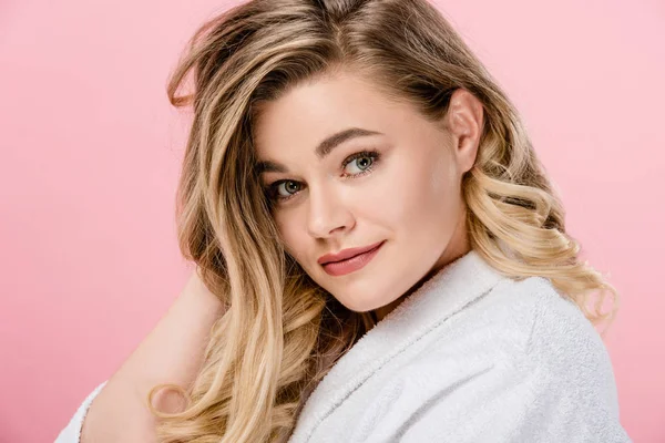 Beautiful young woman in bathrobe smiling at camera isolated on pink — Stock Photo