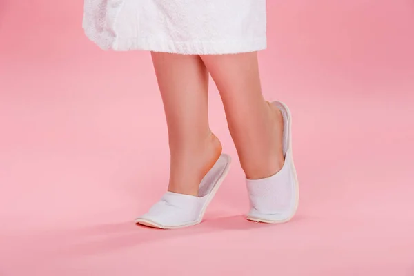 Section basse de jeune femme en surpoids en pantoufles blanches et peignoir sur rose — Photo de stock