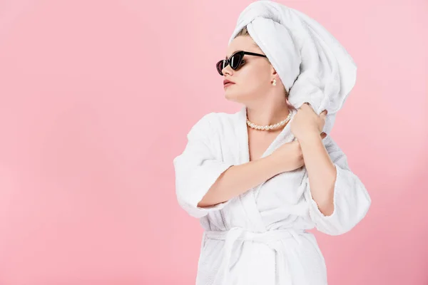 Jovem mulher grande em roupão de banho, óculos de sol e toalha na cabeça olhando para longe isolado em rosa — Fotografia de Stock
