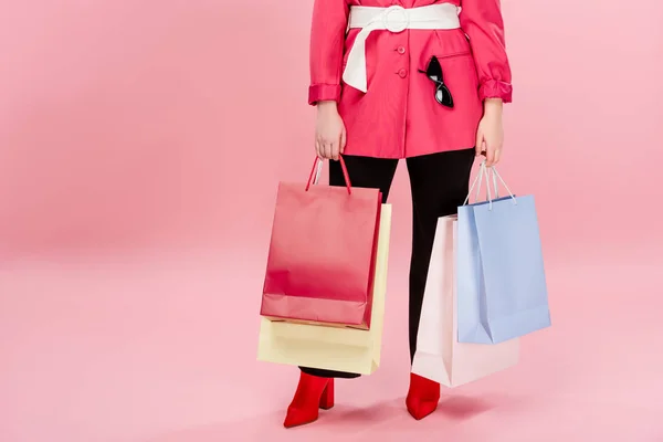 Обрезанный снимок стильной крупногабаритной женщины, держащей сумки на розовом — стоковое фото