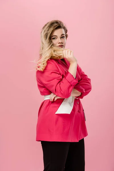 Hermosa joven más mujer de tamaño en chaqueta rosa mirando a la cámara aislada en rosa - foto de stock