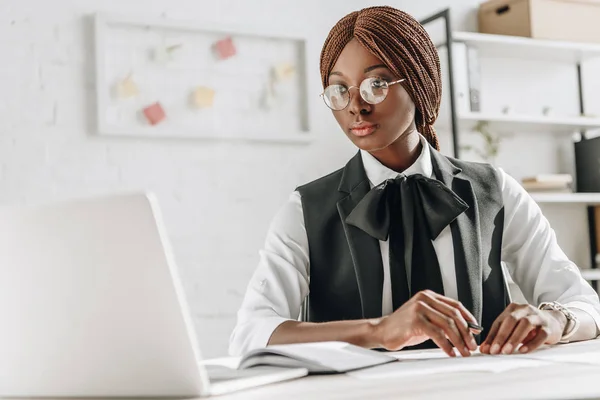 Attraente donna d'affari afro-americana adulta in occhiali seduta alla scrivania del computer e che lavora in ufficio — Foto stock