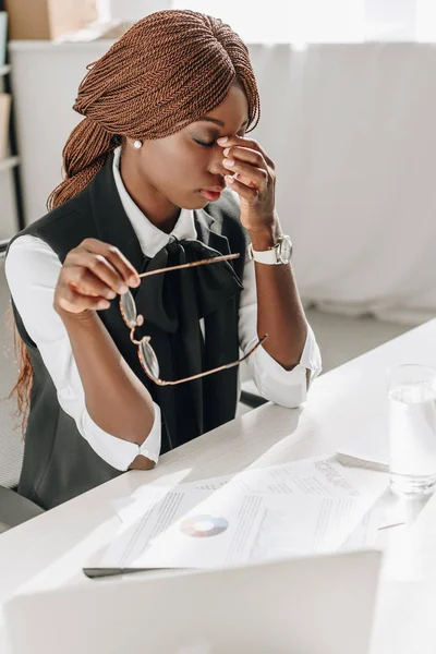 Sick african american adult businesswoman touching her forehead and feeling unwell at workplace — Stock Photo