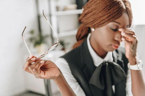 Sick african american adult businesswoman touching her forehead and feeling unwell at workplace — Stock Photo