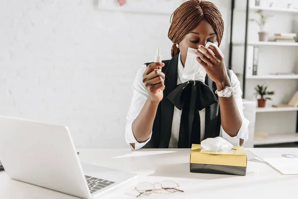 Больная африканская взрослая американская бизнесвумен, страдающая от холода и использования тканей на рабочем столе в офисе — стоковое фото