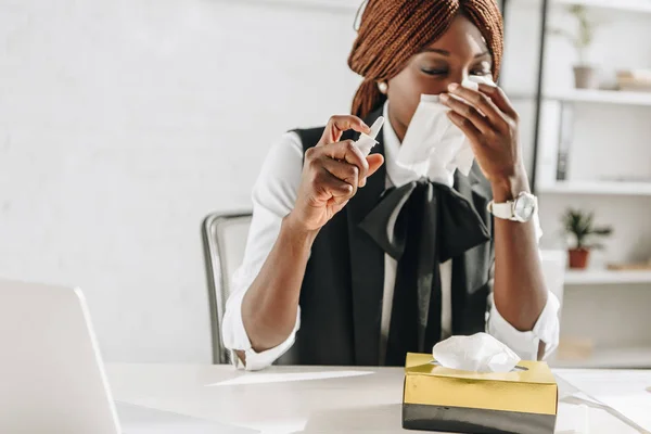 Sick african american adult businesswoman suffering from cold and using tissues at desk in office — Stock Photo