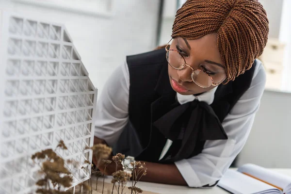 Arquitecta adulta afroamericana enfocada en gafas y ropa formal trabajando en proyecto de construcción - foto de stock