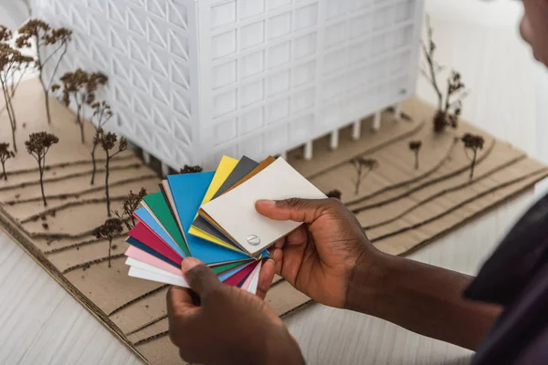 Vista recortada del arquitecto adulto afroamericano sosteniendo paletas de colores y trabajando en proyecto de construcción - foto de stock