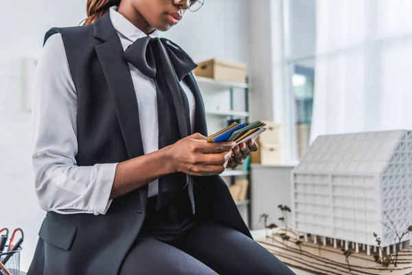 Cropped view of african american adult female architect holding color palettes and working on construction project — Stock Photo