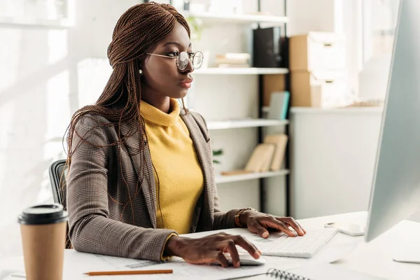 Fokussierte afrikanisch-amerikanische Geschäftsfrau sitzt am Computer-Schreibtisch und arbeitet im Büro — Stockfoto