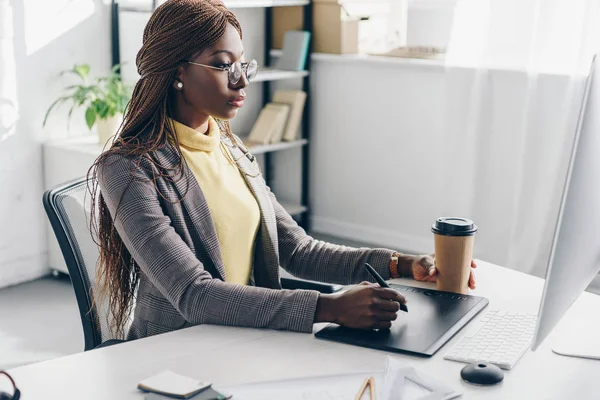 Elegante erwachsene afrikanisch-amerikanische Geschäftsfrau sitzt am Computer-Schreibtisch und benutzt am Arbeitsplatz ein Grafik-Tablet — Stockfoto