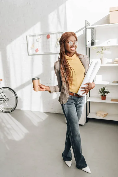 Щасливі афро-американських дорослих жіночий архітектором в окуляри, які тримають кавові йти і креслення на робочому місці — стокове фото