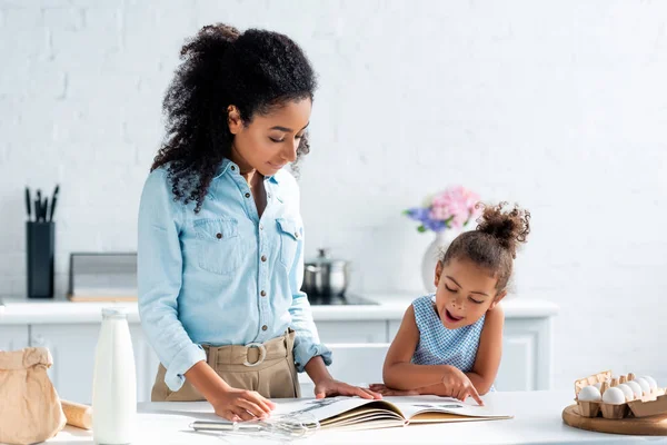 Afro americano madre e figlia guardando ricettario in cucina — Foto stock