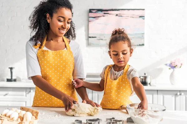 Sonriente afroamericana madre e hija amasando masa de postre en la cocina - foto de stock
