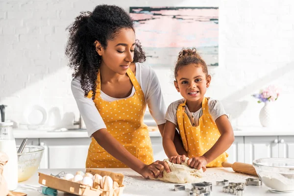 African american mother and daughter kneading dough for homemade dessert in kitchen — Stock Photo